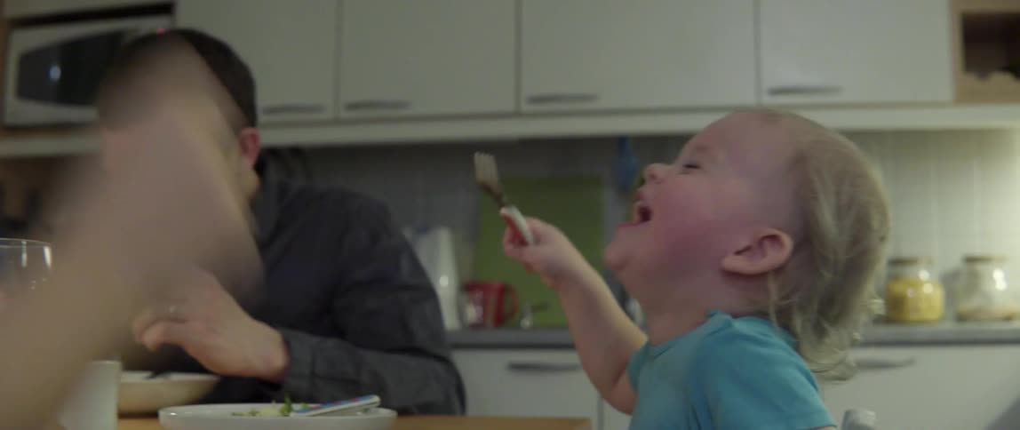 Toddler giving a woman a bite of food and then laughing