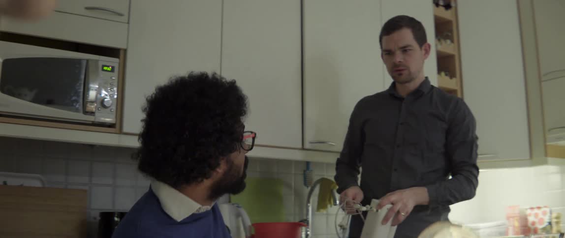 Group of friends sitting in a modern kitchen talking and laughing during social gathering