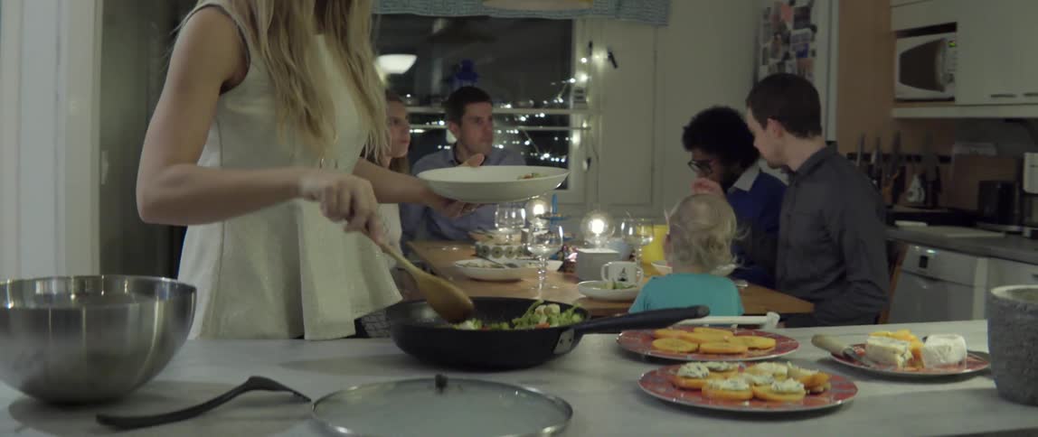 Woman standing and spooning food into a bowl with focused kitchen moment