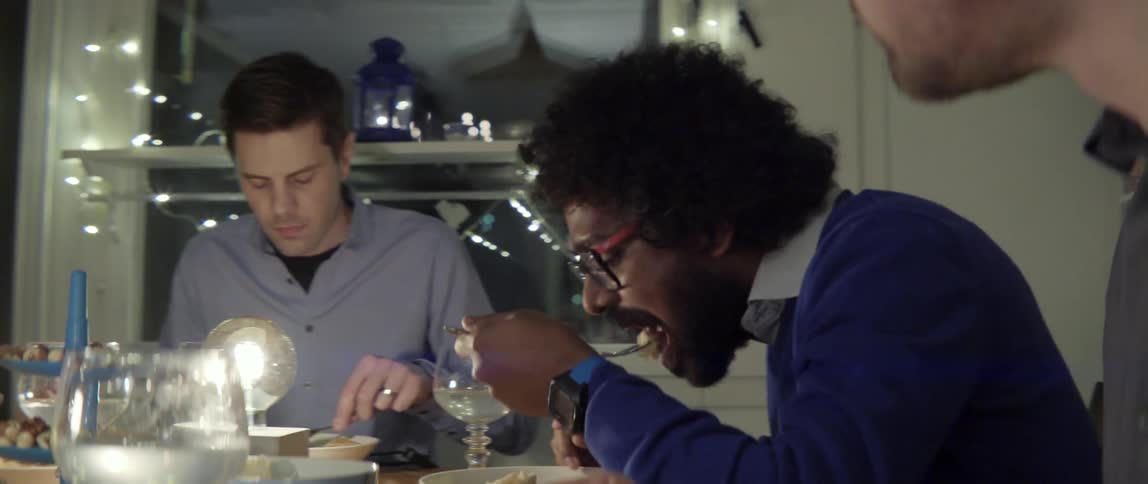 Authentic lifestyle footage of people sharing a meal and laughing together at night time.