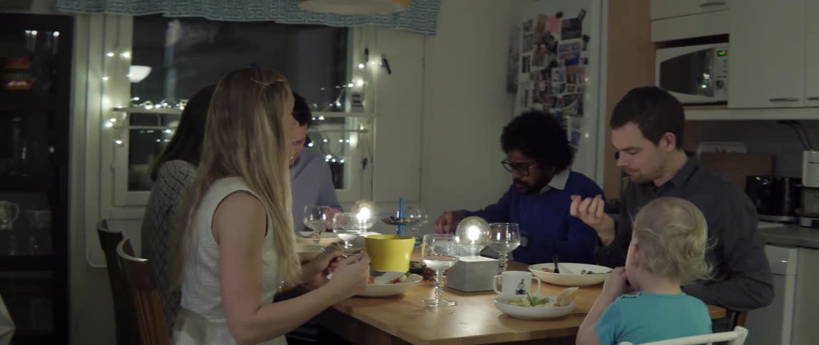 Diverse group of friends sharing a healthy meal together during an evening dinner party.