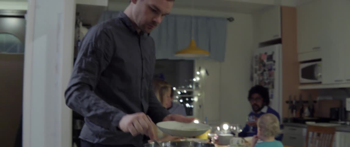 Young man leaving a group dinner table to serve himself more fresh healthy food