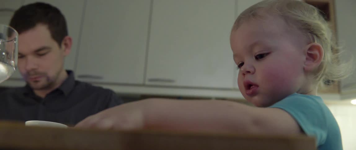 Father watching his young child eat a healthy meal during a family dinner party.