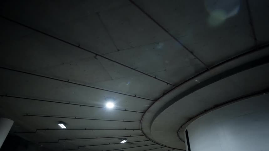 A large column sits under a curved bridge