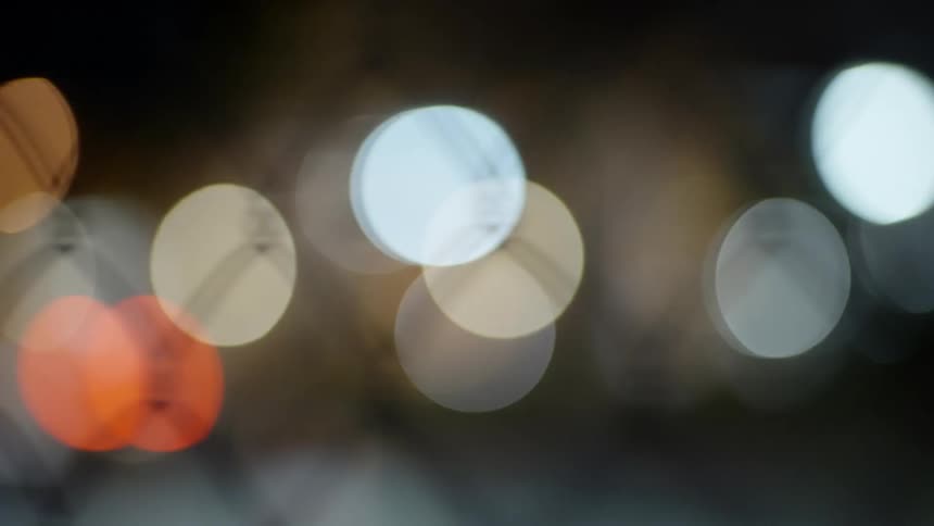 Blurred lights shine through a chain link fence