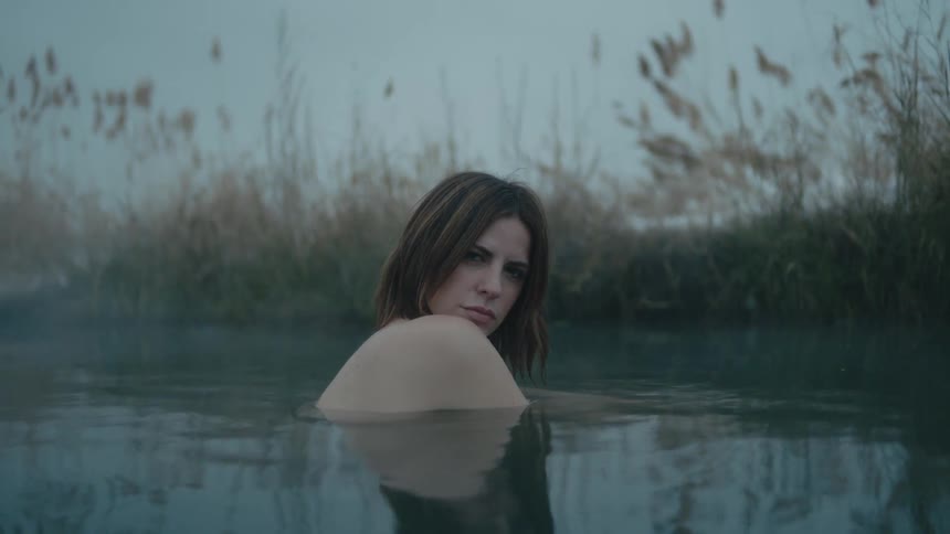 Young woman in a lake surrounded by fog she is covered by the water with only the shoulders and head out