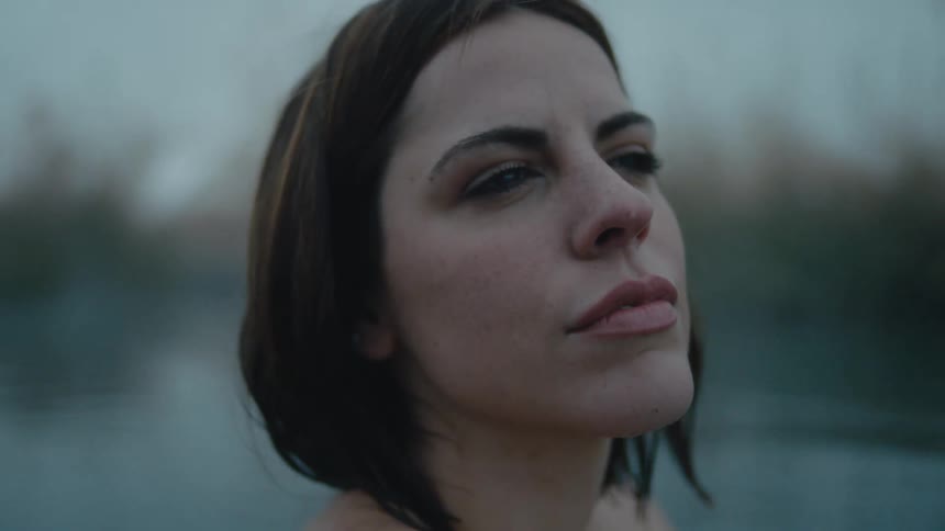 A woman rubs her hand on her shoulder as she stands in a body of water