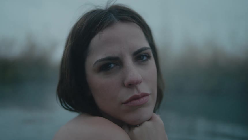 A woman sitting in a hot spring pond looking romantic