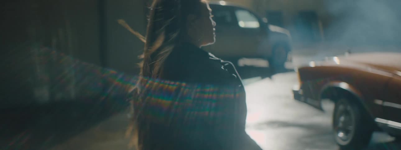 Woman walks across parking lot taking down her pony tail before she arrives at car