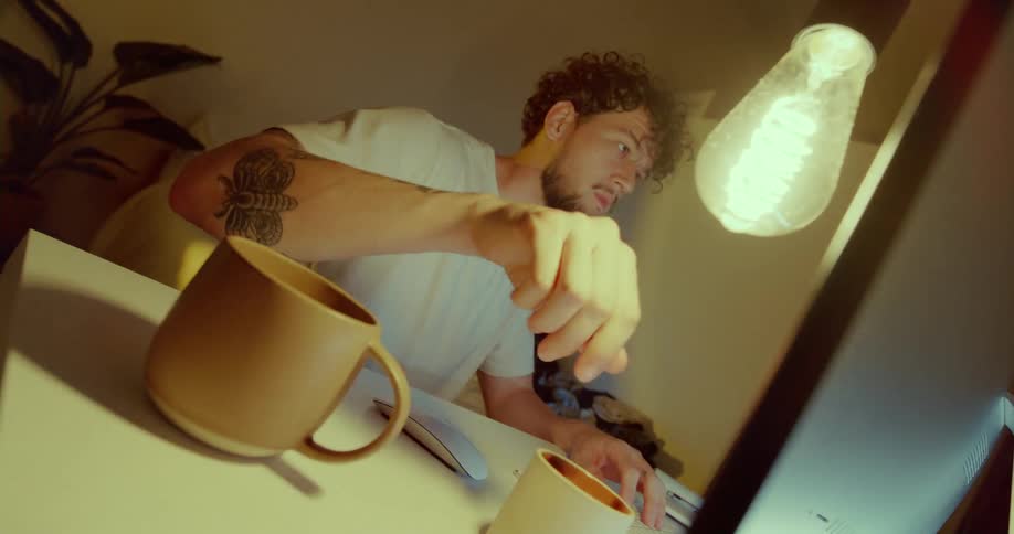 Man typing at desk stops briefly to turn on light