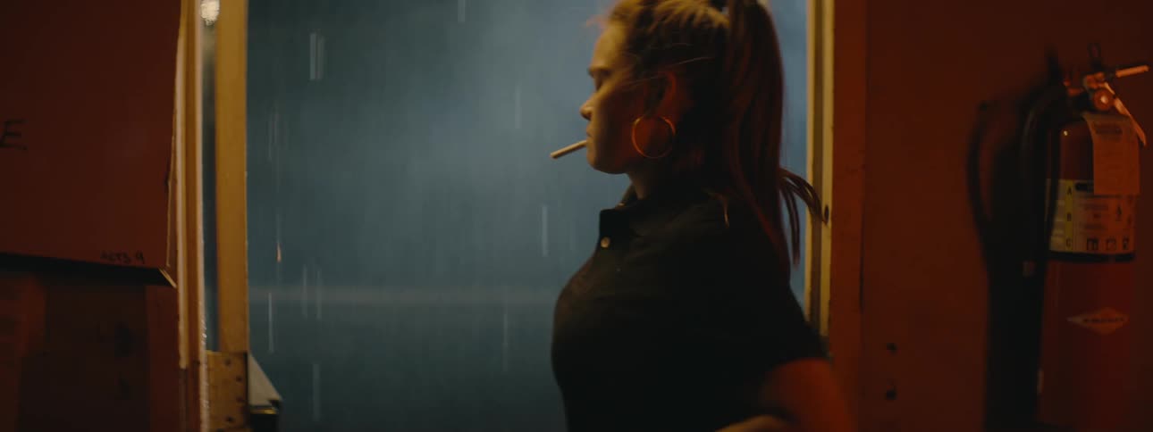 A woman slams a door open aggressively and lights a cigarette