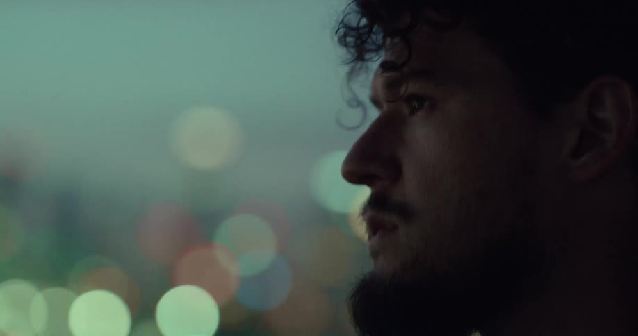 A man turns his head looking at the city lights at night