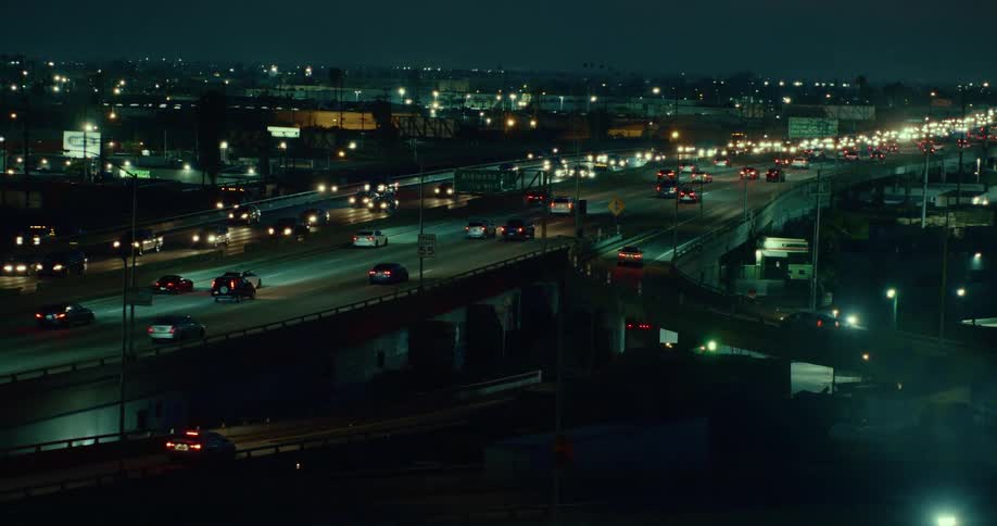 Heavy traffic passes through a city on a highway at night