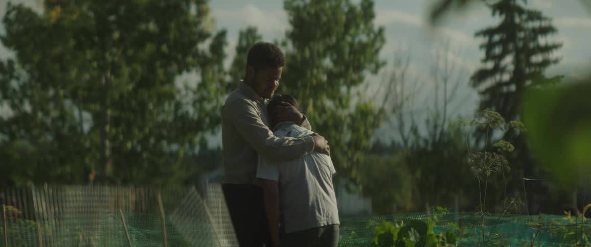 A man hugs a crying child before leading the boy out of frame