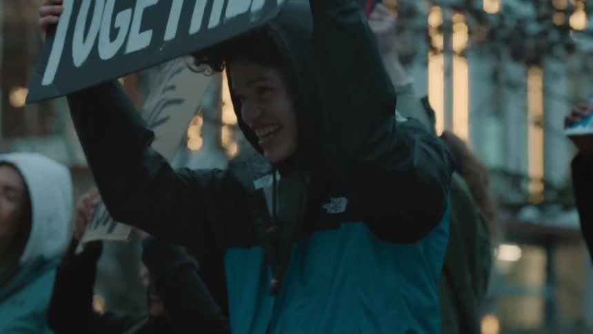 A group of people walk down a city carrying signs during a rally