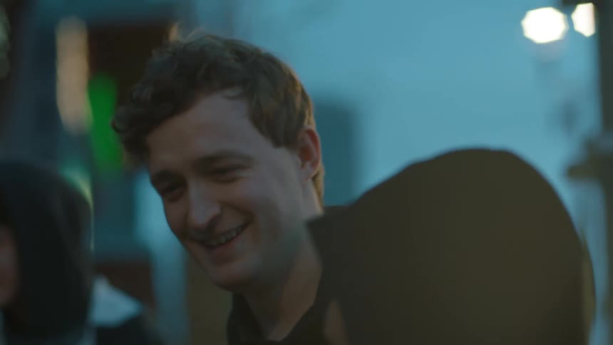 A teenage boy talks with friends outside in the evening