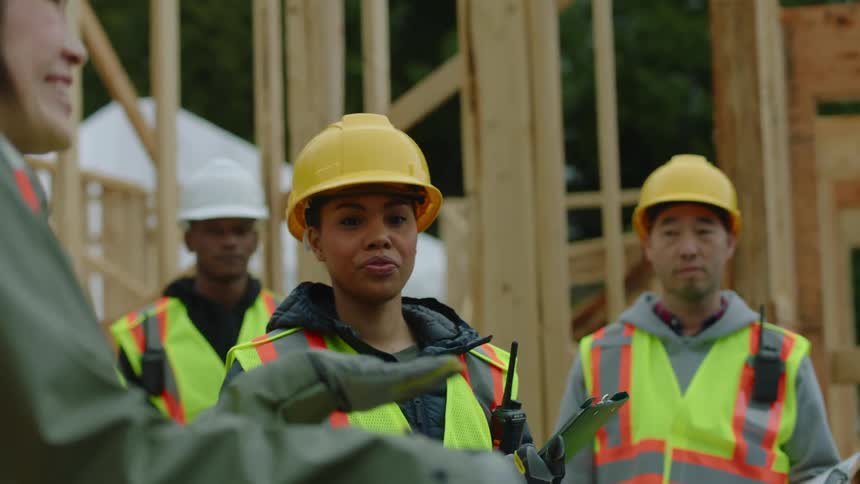 A female construction foreman instructs employees what to do at a job site
