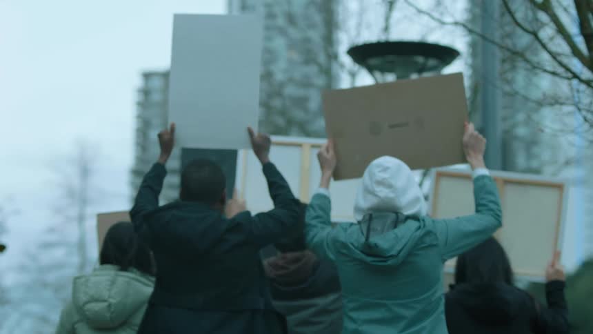 A group of people hold signs and march in protest