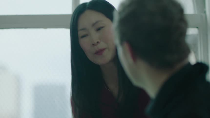 A man and woman talk in an office as they look at his laptop