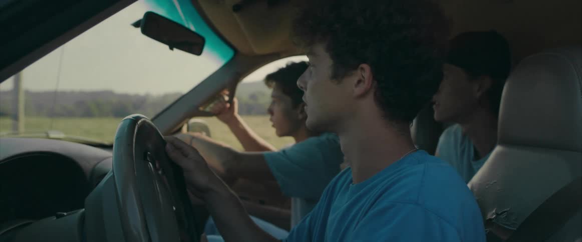 Three teenage boys drive around in a truck in a rural area