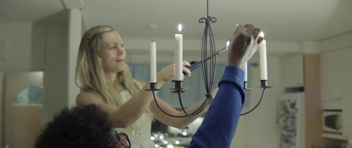 Man and Woman Lighting a Candle Chandelier Together in a Warm Intimate Moment.