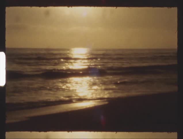 Ocean waves stretching from beach to the horizon reflect the bright sunlight