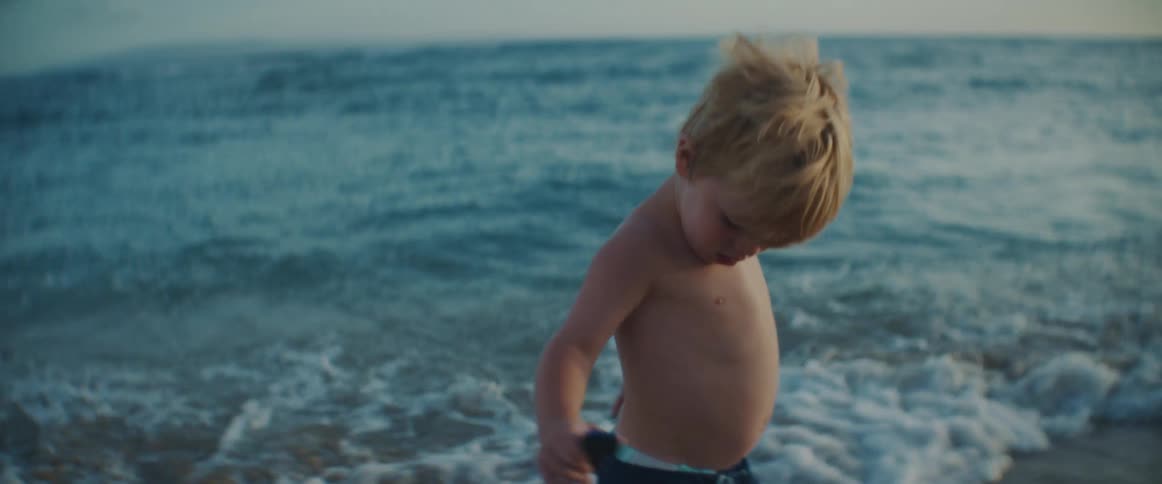 A little boy runs along the beach with his sister