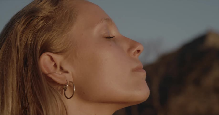 Blonde woman with earrings opens her eyes looking up