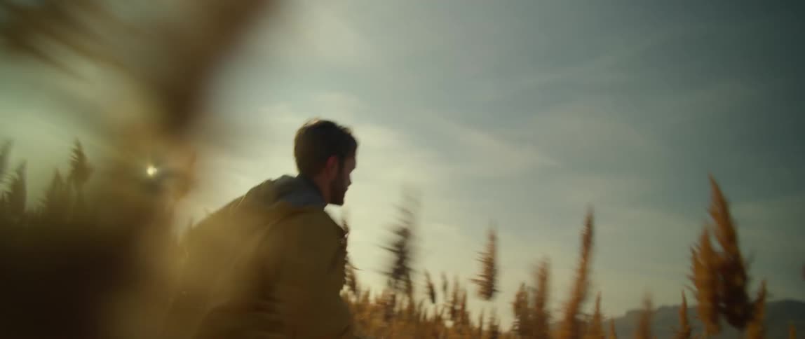 A young man runs through a field as he looks around his surroundings