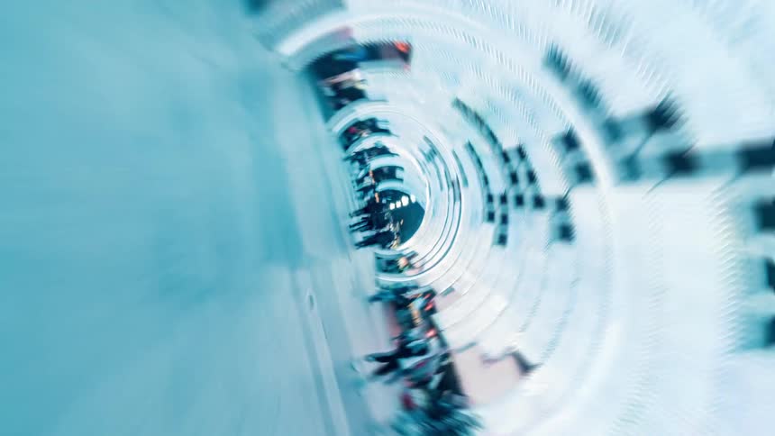 Pedestrians walk through light tunnel situated near stores in city at night