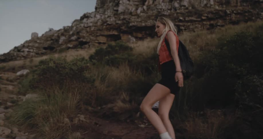 A woman is hiking outdoors through a mountainous area