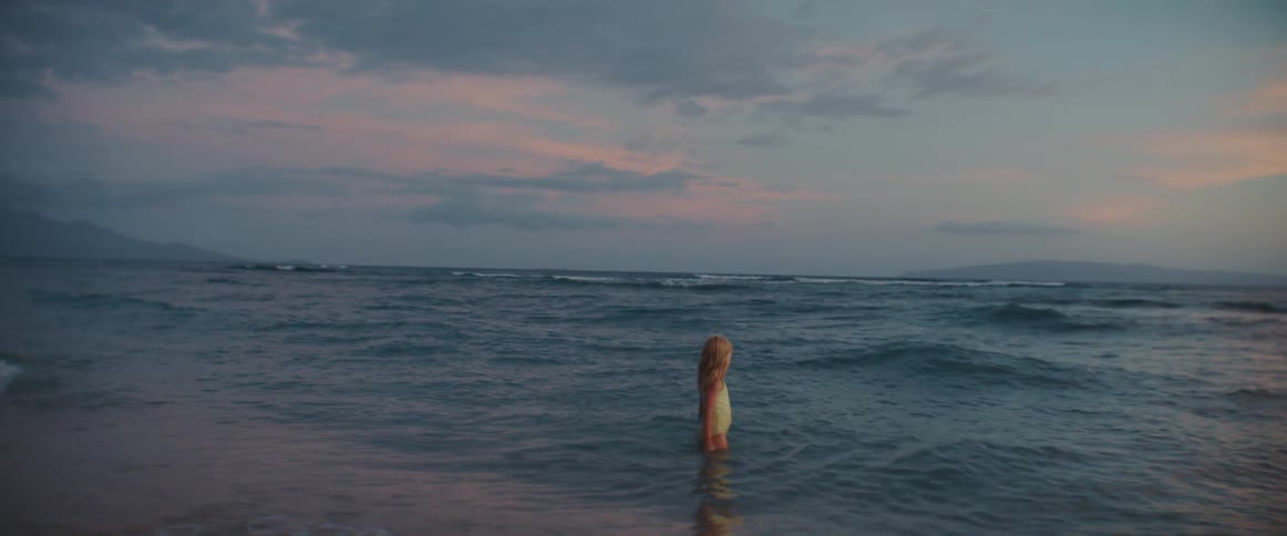 Little girl walking in the sea at an empty beach during sunset