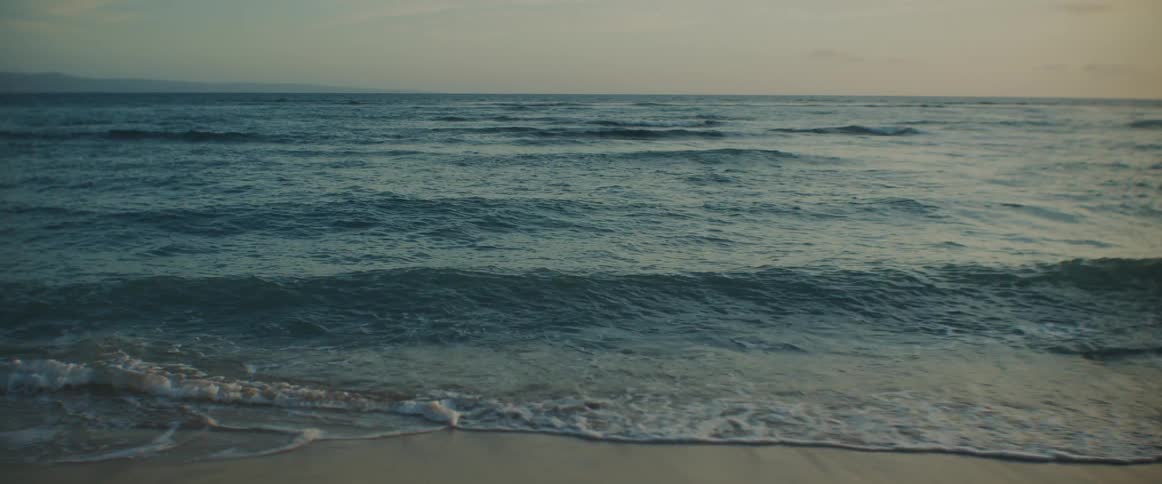 Waves are rolling into shore and over the sand on the beach