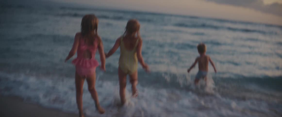 A group of young children run into the ocean water