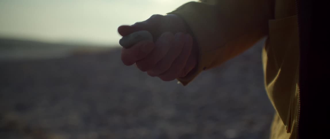 Close up of a man as he picks up a rock and throws it