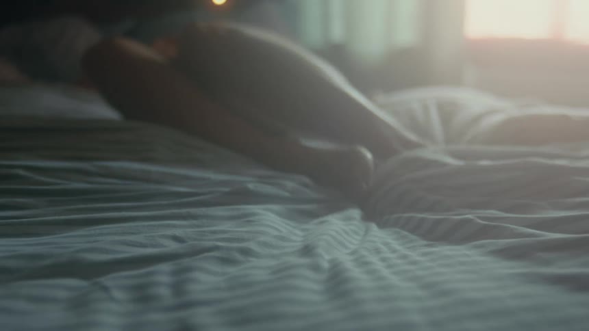 A woman is laying down in her bed during the morning