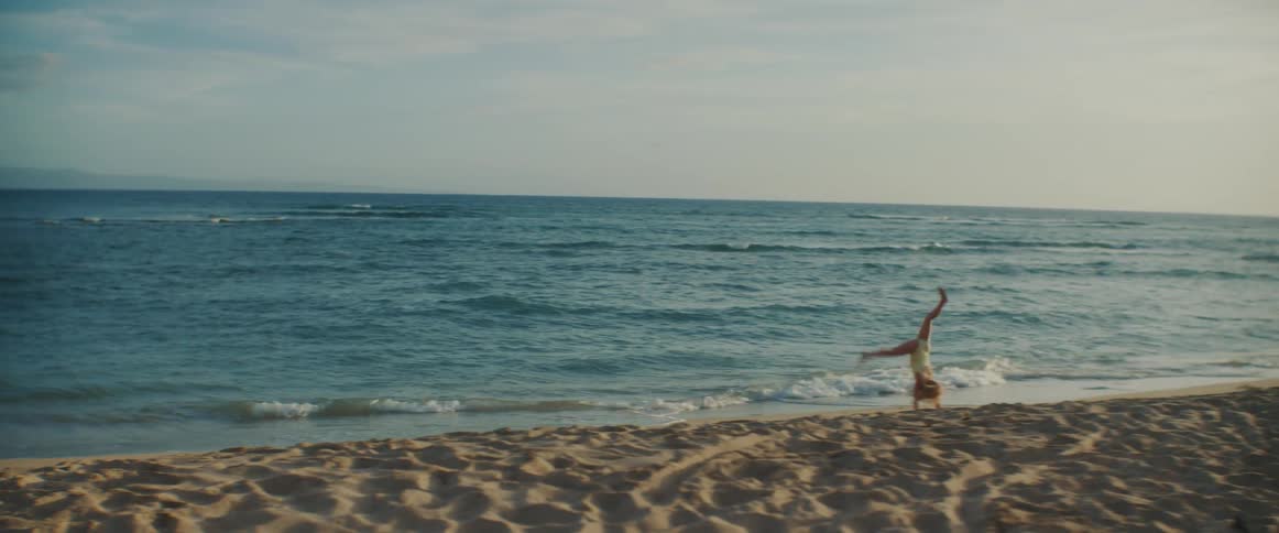 Girl running on the beach near the sea and doing cartwheels at a sunny day