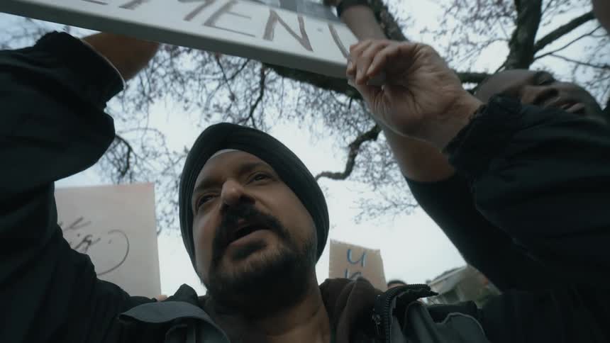 A man holds up a sign and chants as he marches with others during a protest