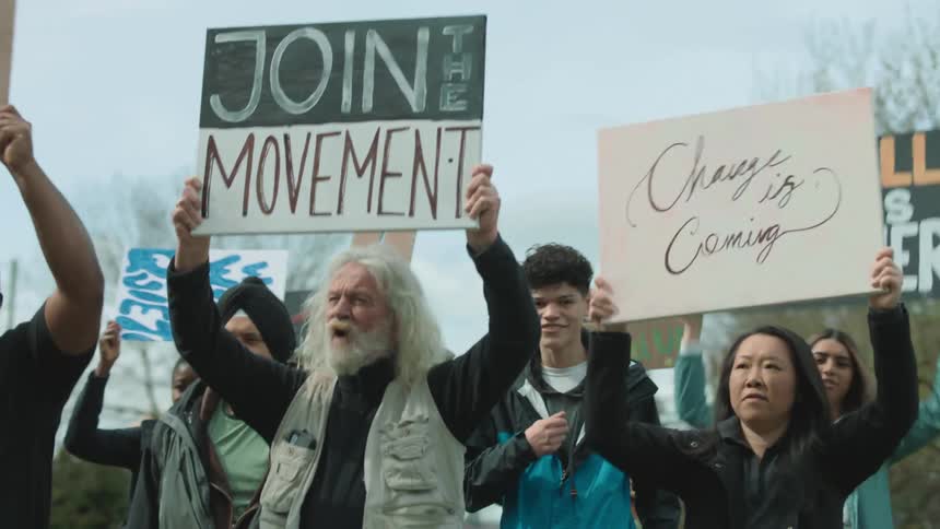 A group of protesters chant together as they walk through a city carrying signs