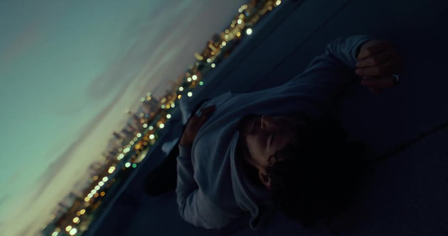 A teenage boy lays down as he looks over a city