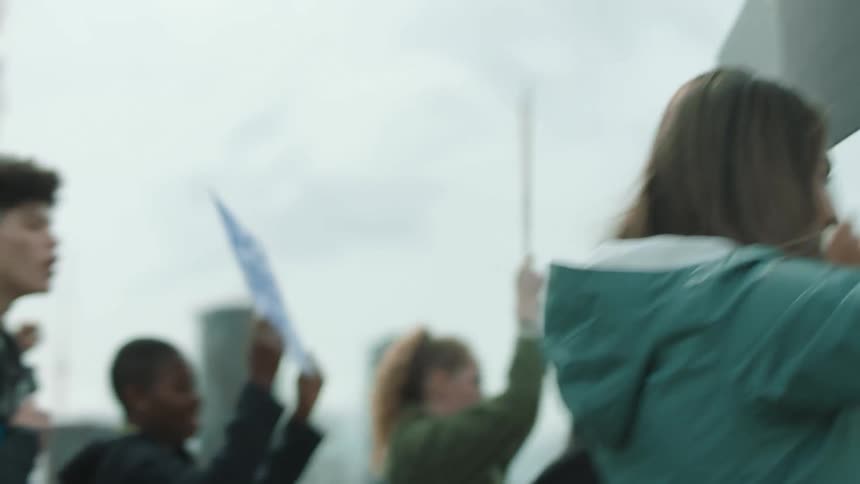 A group of people hold signs up as they march in a park