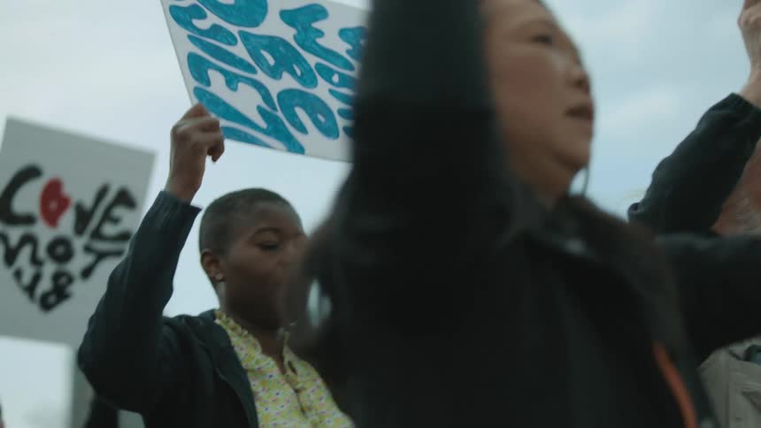 A group of people march holding signs for equality