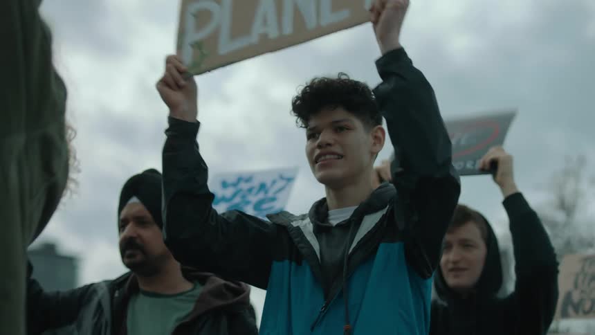 People wave signs in the air at a protest