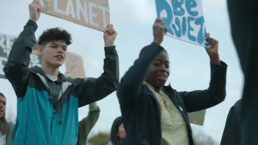 A woman speaks into a megaphone as a group marches and protests with signs