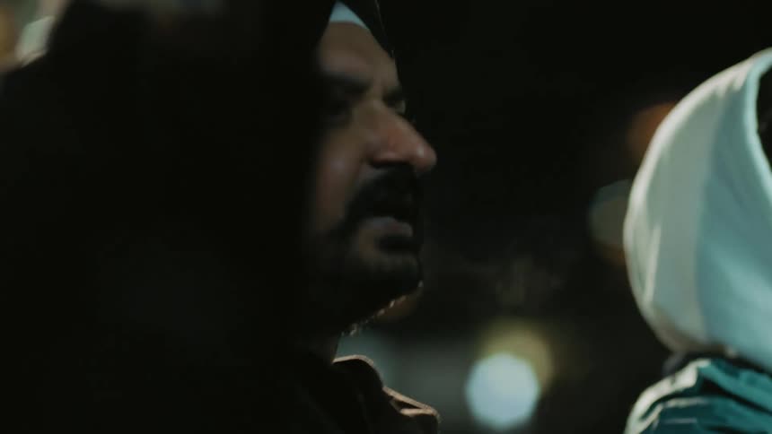 A man shakes his arm in the air and yells during a protest at night