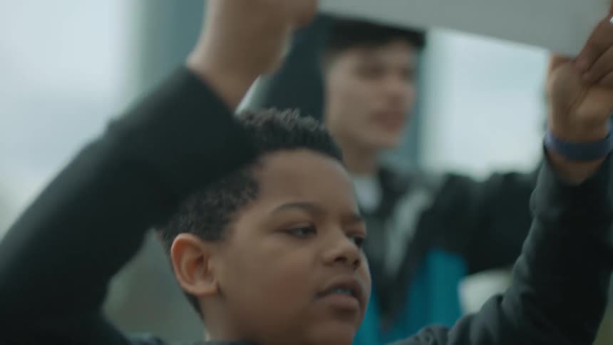 A young boy holding up a sign and chanting along with a group of protestors
