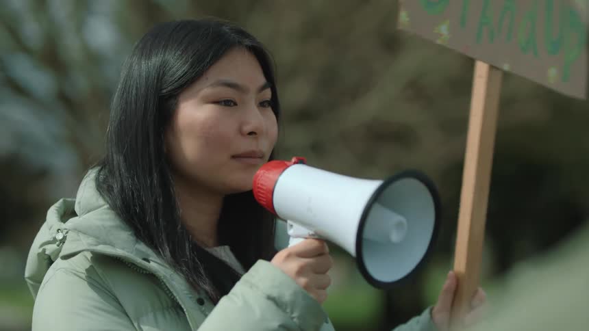 A woman speaks into a megaphone as other people cheer