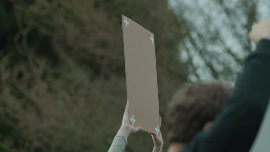 Hands holding up a blank protest sign next to a protester with his fist in the air