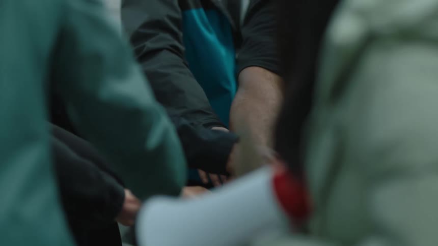 A group of people place their hands in a circle together
