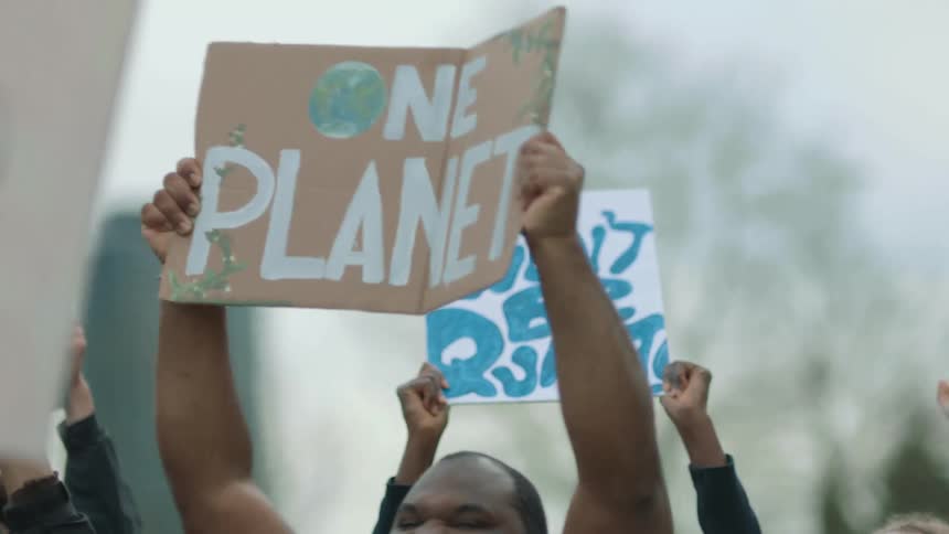 People hold signs up in the air and yell at a rally